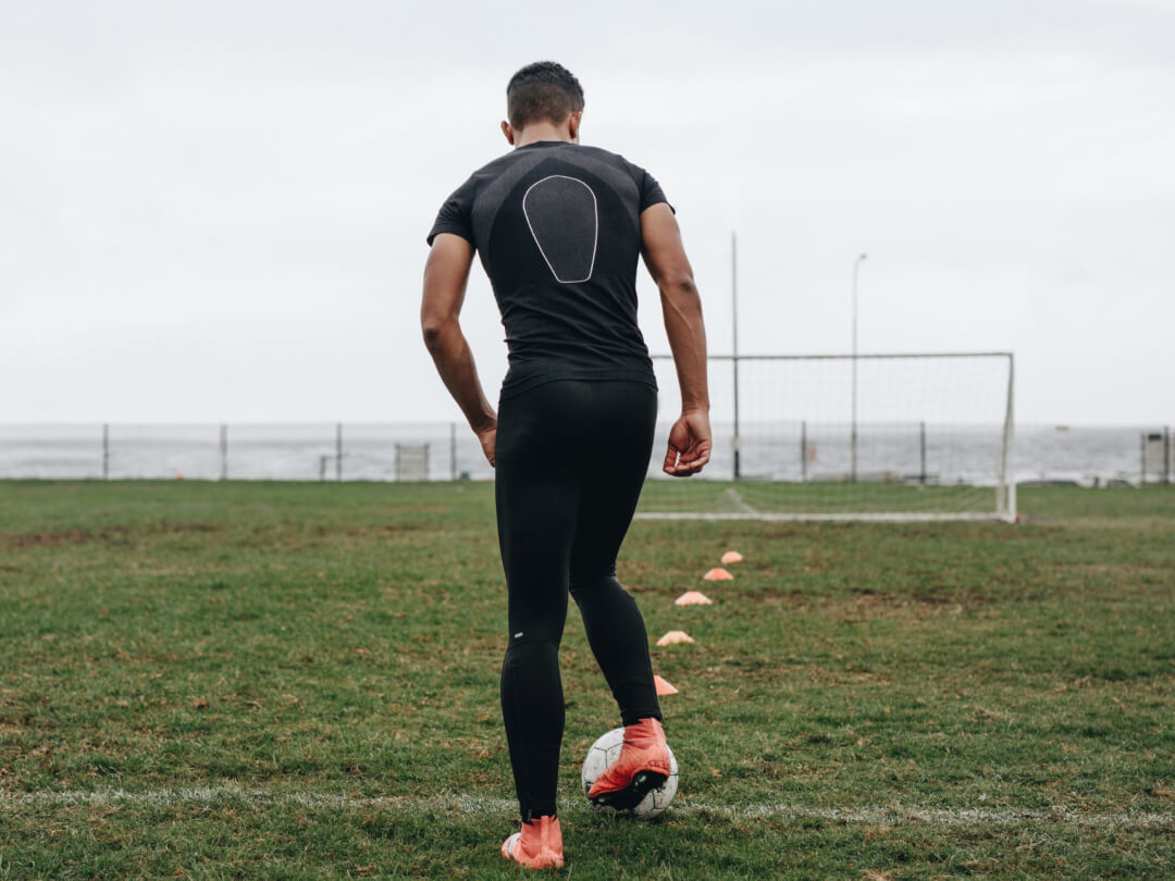 A soccer player is standing on a field with a ball.