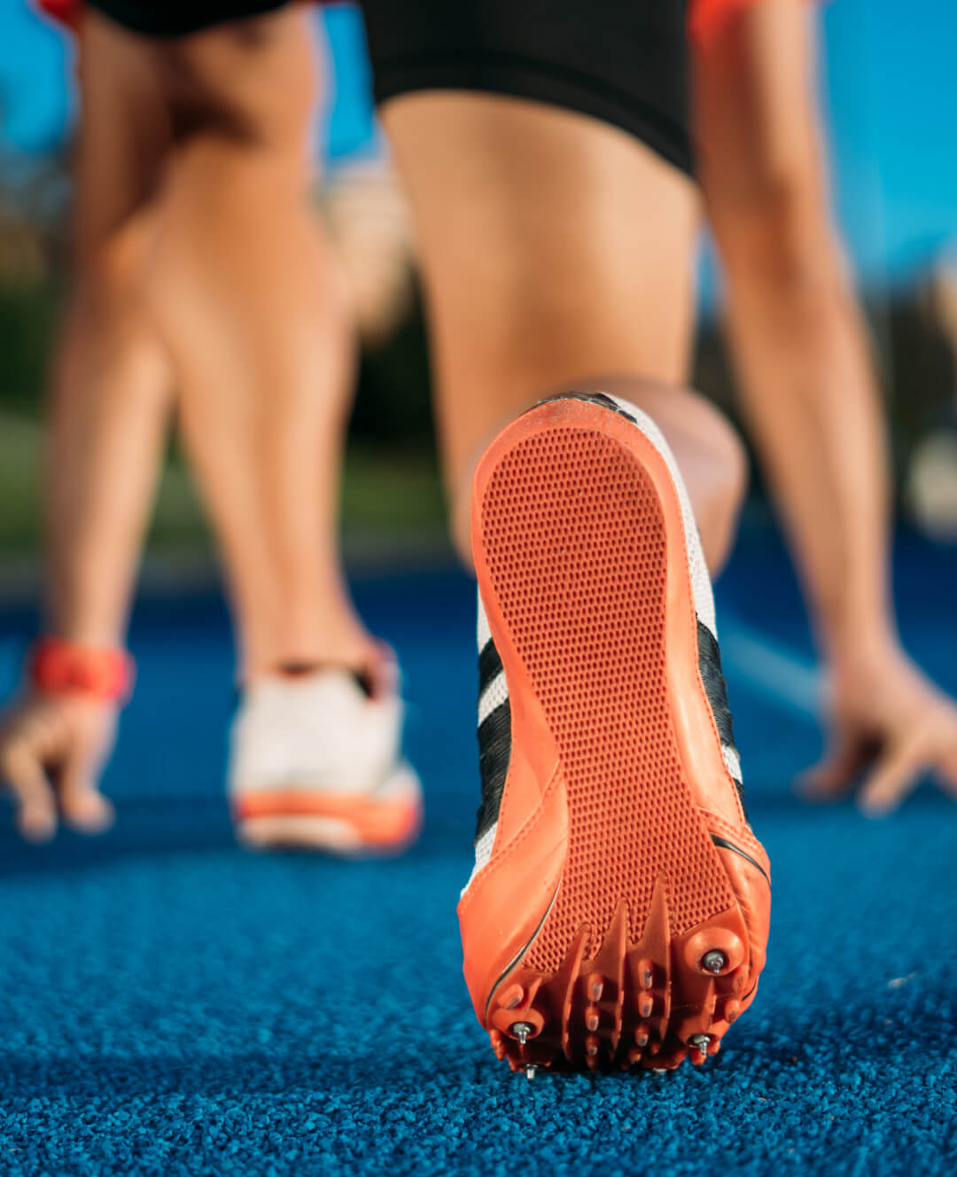 The feet of a person running on a track.