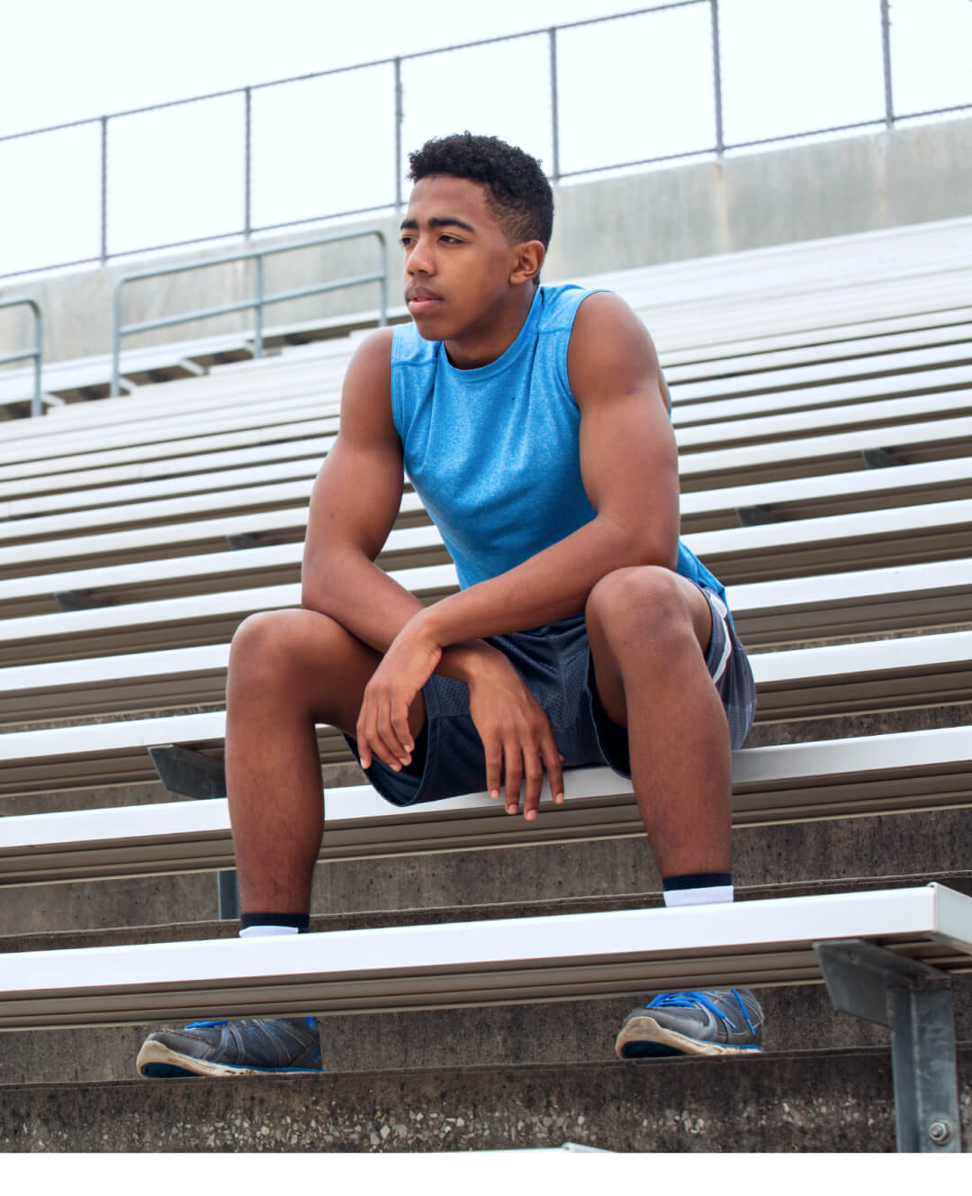 A young man sitting on the bleachers of a stadium.