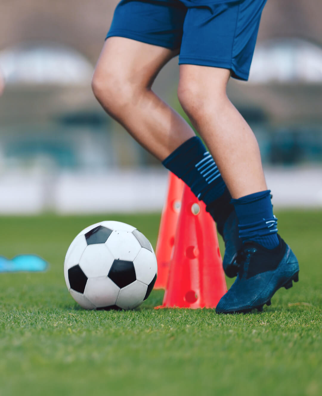 A soccer player is kicking a ball on a soccer field.